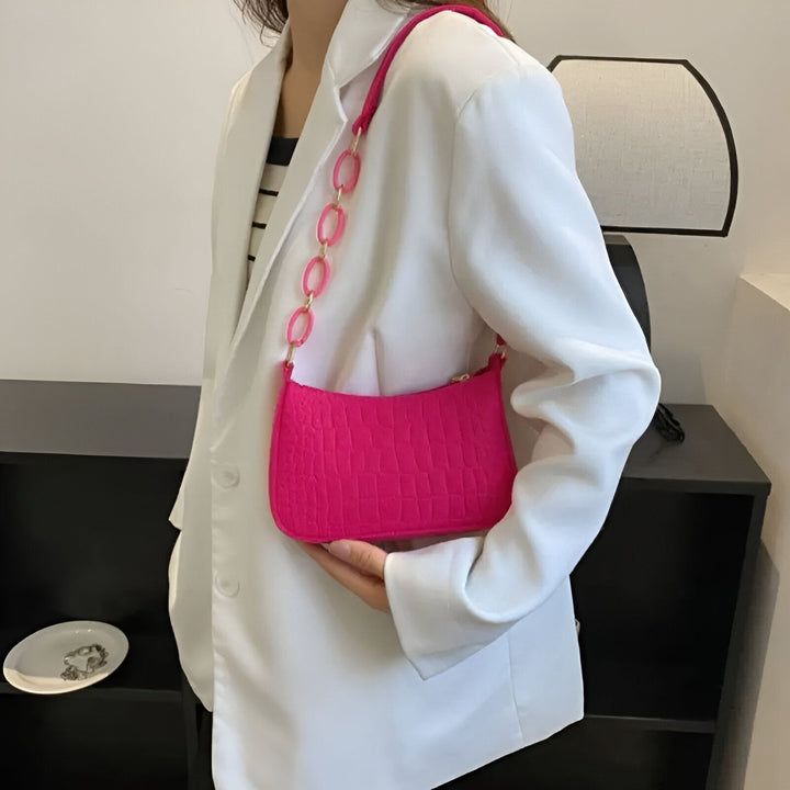 Sac rose vif texture croco avec anse chaîne rose porté avec un blazer blanc., 46193938596064,46193938628832,46193938661600,46193938694368