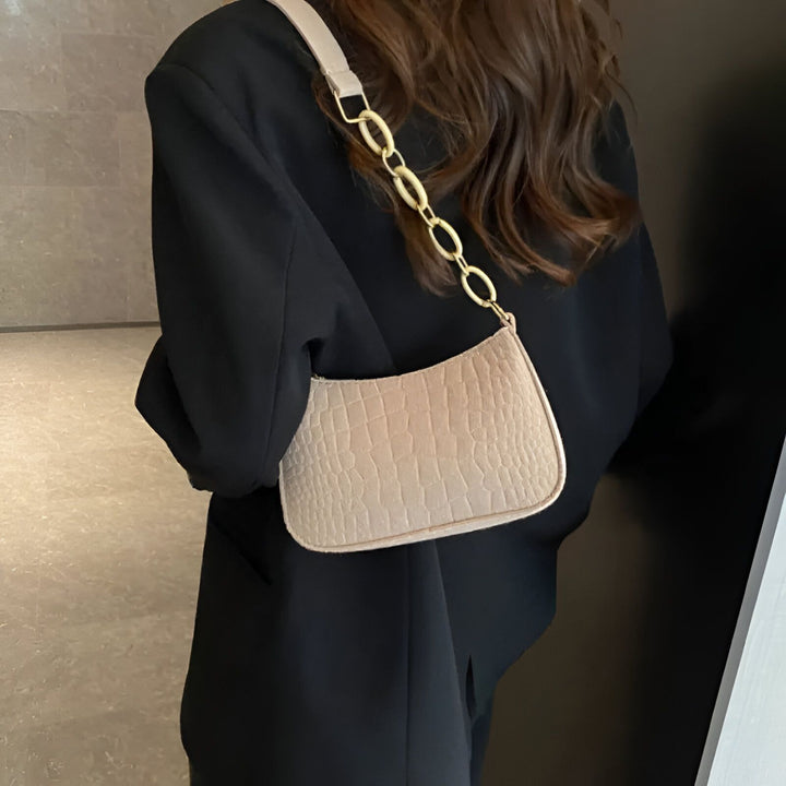 Femme en blazer noir portant un sac beige motif croco avec anse chaîne dorée sur l'épaule., 46193938596064,46193938628832,46193938661600,46193938694368