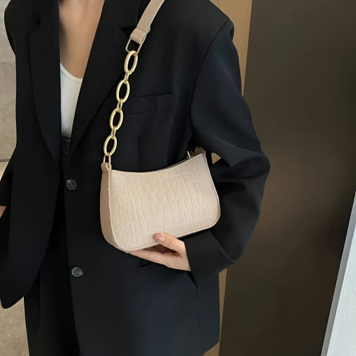 Sac à main beige effet croco avec chaîne dorée porté par une femme en blazer noir., 46193938596064,46193938628832,46193938661600,46193938694368