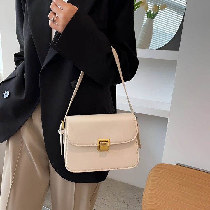 Sac à bandoulière crème avec fermoir doré porté par une personne en blazer noir., 46194027069664,46194027102432,46194027135200,46194027167968