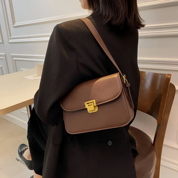 Sac bandoulière marron en cuir avec fermoir doré, porté par une femme en blazer noir., 46194027069664,46194027102432,46194027135200,46194027167968