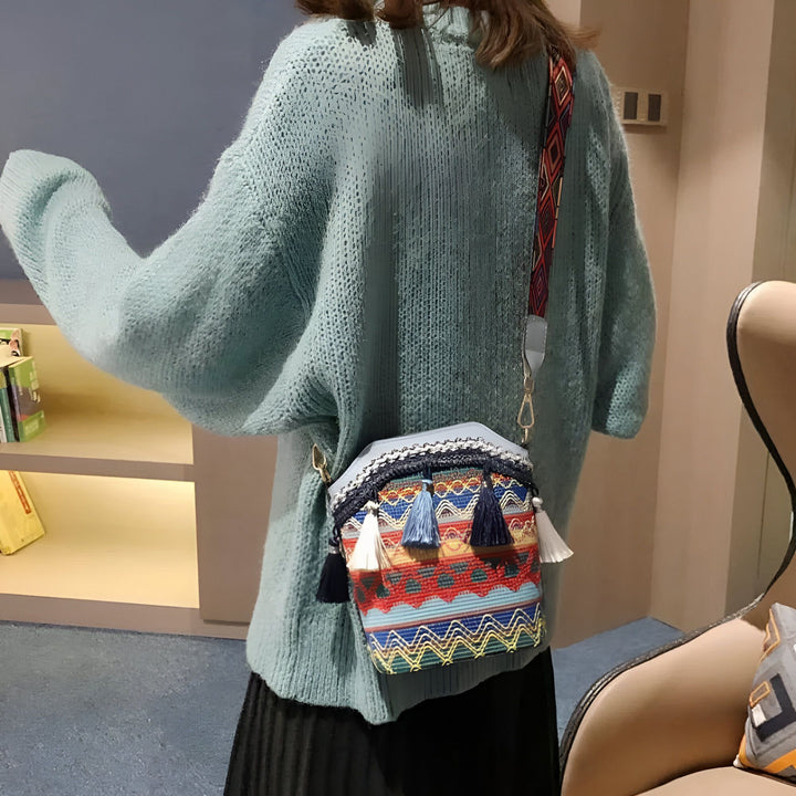 Sac bandoulière coloré à motifs ethniques et pompons porté avec pull bleu et jupe noire., 46193925193952,46193925226720,46193925259488,46193925292256