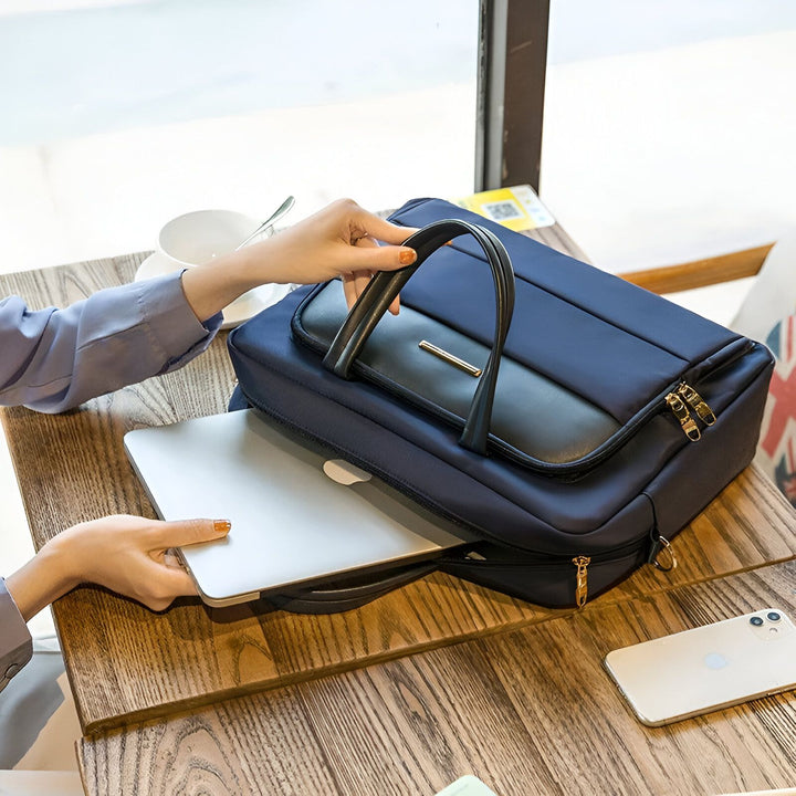 Femme rangeant un ordinateur portable argenté dans un sac bleu marine sur une table en bois., 46193906057440,46193906090208,46193906122976,46193906155744,46193906188512,46193906221280,46193906254048,46193906286816,46193906319584,46193906352352,46193906385120,46193906417888,46193906450656,46193906483424,46193906516192