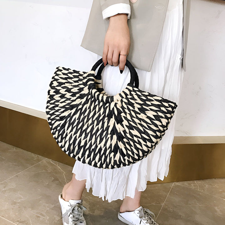 Sac en paille tissée noir et blanc avec poignées, tenu par une personne., 46194029494496,46194029527264,46194029560032,46194029592800
