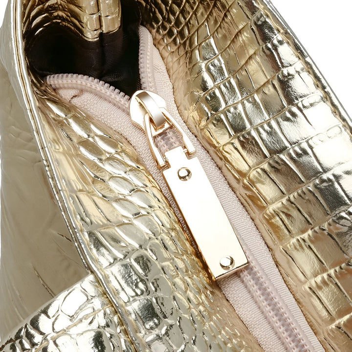 Détail d'un sac doré texturé imitation crocodile avec une fermeture éclair dorée., 46194033852640