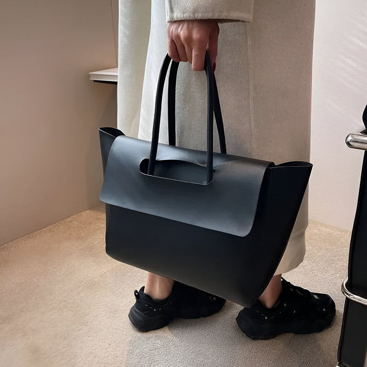 Une personne porte un grand sac cabas noir et des baskets noires., 46194054791392,46194054856928,46194054889696,46194054922464,46194054955232