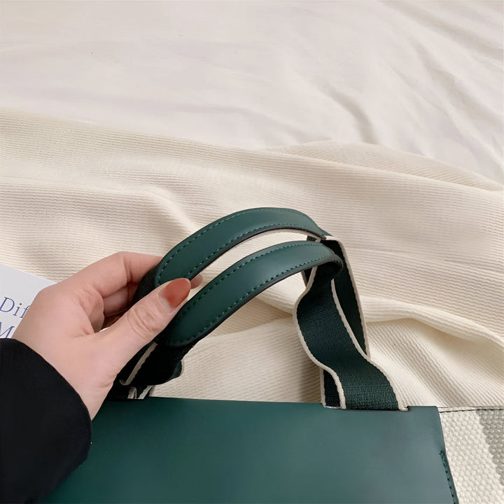 Main tenant les poignées vertes en cuir d'un sac à main avec sangle rayée., 46193896030432,46193896063200,46193896095968,46193896128736