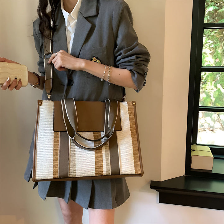 Femme en blazer gris portant un grand sac cabas rayé blanc, beige et marron., 46193896030432,46193896063200,46193896095968,46193896128736