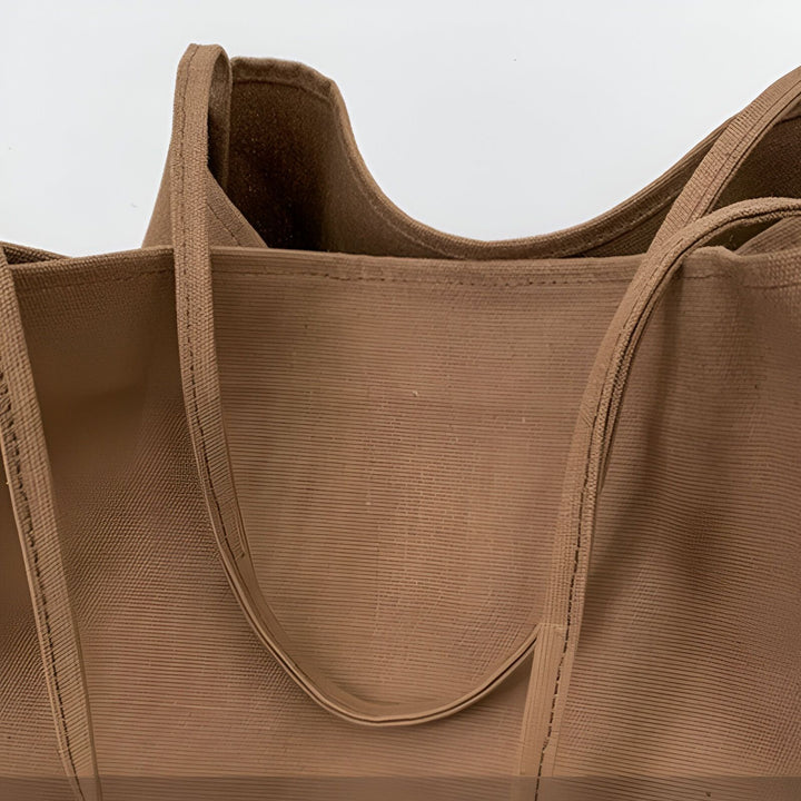 Plan rapproché d'un sac cabas en toile marron avec ses anses. La texture du tissu est visible., 46193893048544,46193893081312