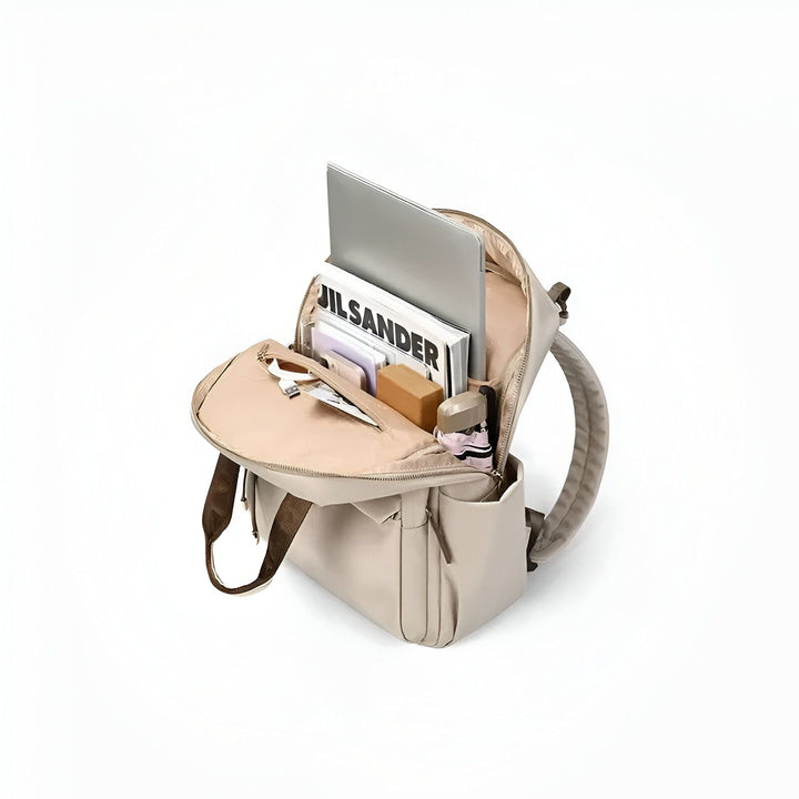 Sac à dos beige ouvert avec ordinateur portable, magazine JILSANDER, livres, écouteurs et mini sneakers., 46193875878112,46193875910880,46193875943648,46193875976416