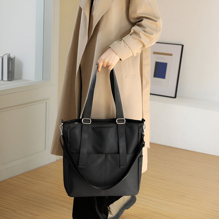Sac tote noir en tissu avec bandoulière, porté par une personne en trench beige., 46193874796768,46193874829536,46193874862304