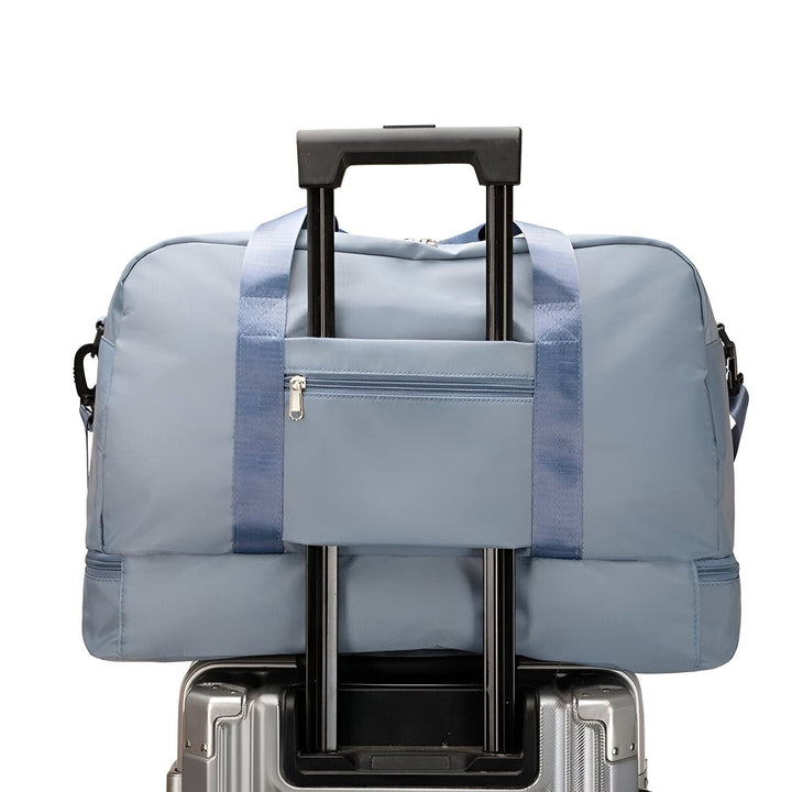 Sac de voyage bleu clair posé sur la poignée télescopique d'une valise argentée., 46193918902496,46193918935264,46193918968032,46193919000800