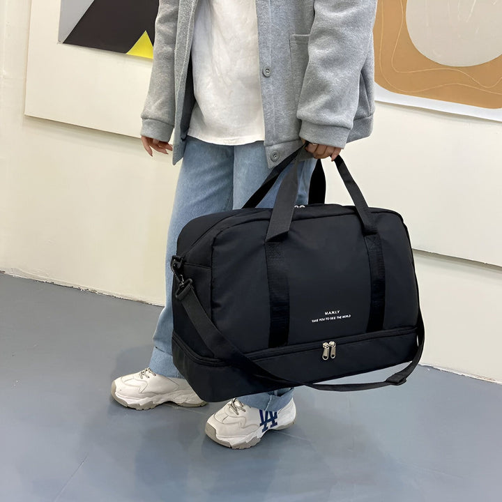 Personne tenant un sac de voyage noir MANLY, 46193918902496,46193918935264,46193918968032,46193919000800