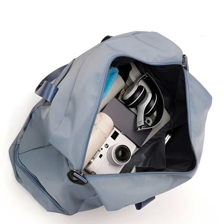 Sac de voyage gris bleu ouvert, contenant un casque audio, un appareil photo et une serviette., 46193918902496,46193918935264,46193918968032,46193919000800