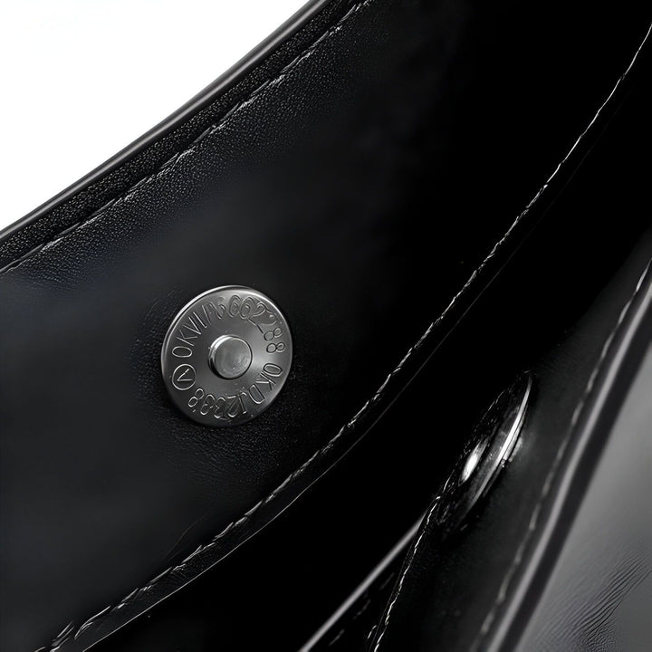 Détail d'un bouton pression métallique sur matière noire texturée avec coutures., 46193861034208