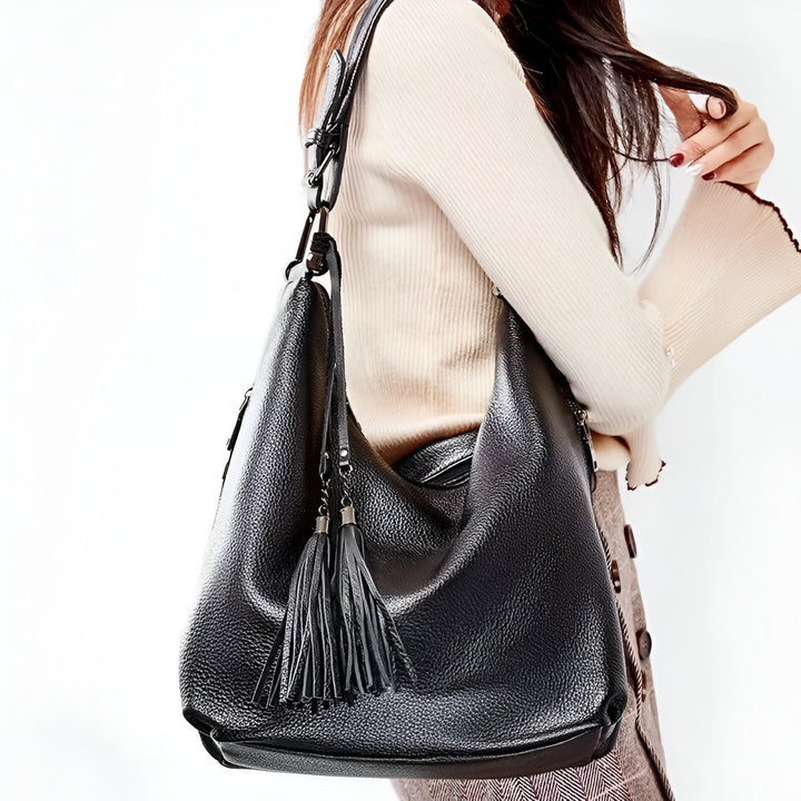 Sac hobo noir en cuir grainé à pompons porté par une femme., 46193838129376,46193838162144,46193838194912,46193838227680,46193838260448,46193838293216,46193838325984