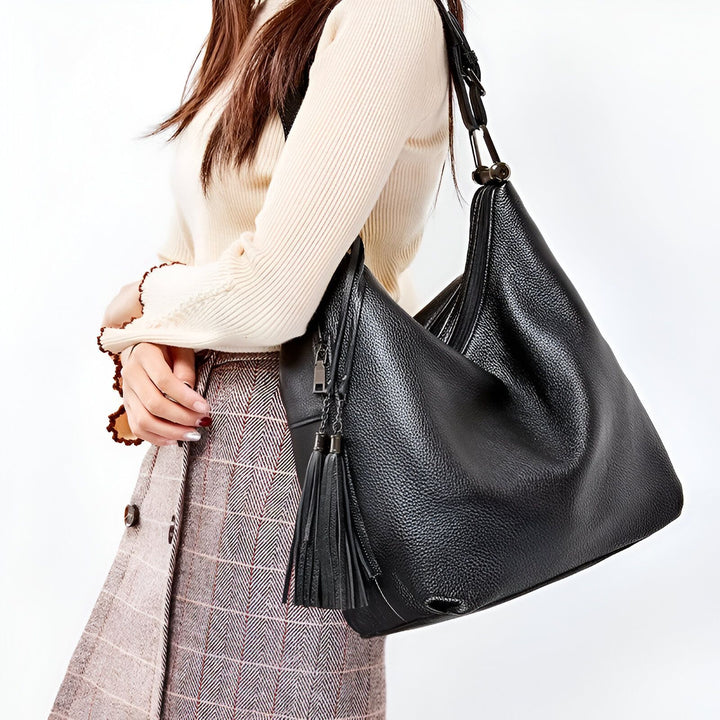 Sac hobo en cuir grainé noir avec pompons porté par une femme, 46193838129376,46193838162144,46193838194912,46193838227680,46193838260448,46193838293216,46193838325984