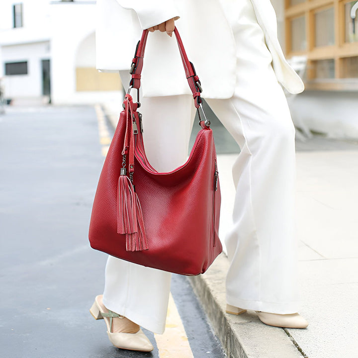 Femme en blanc tenant un grand sac hobo en cuir rouge avec pompons., 46193838129376,46193838162144,46193838194912,46193838227680,46193838260448,46193838293216,46193838325984