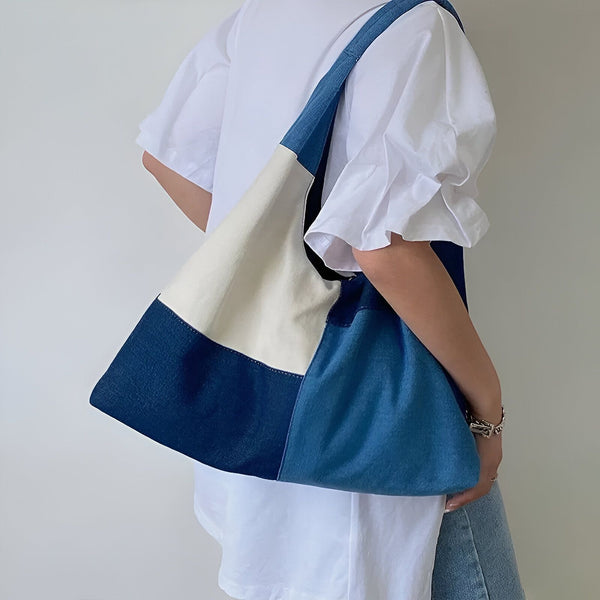 Personne portant un sac cabas bicolore beige et bleu sur l'épaule., 46193996628192