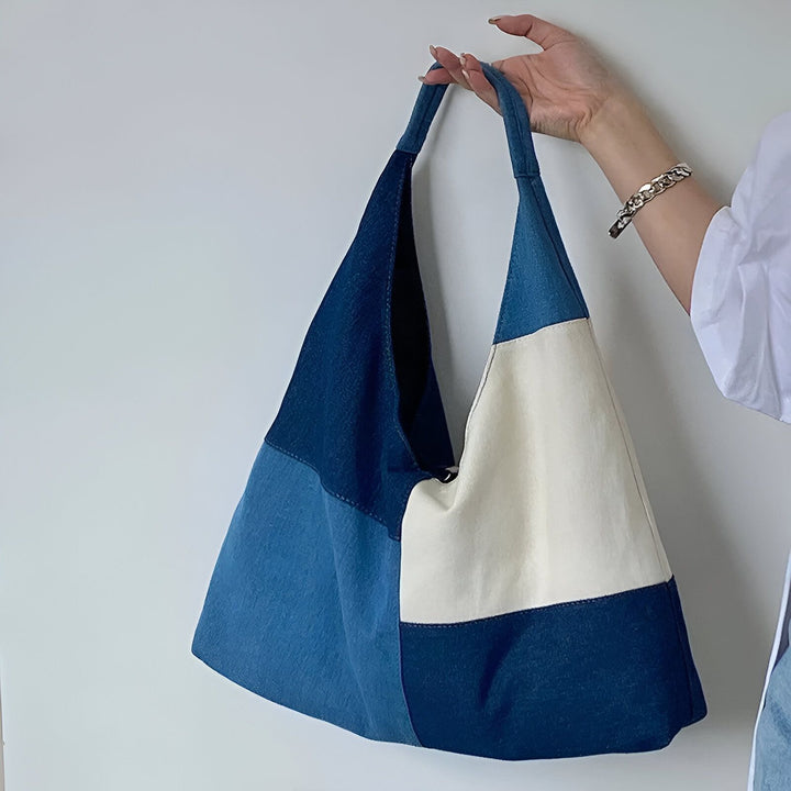 Sac cabas patchwork en denim bleu et toile crème tenu par une main., 46193996628192
