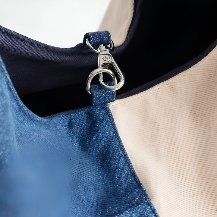 Mousqueton chromé sur un sac en tissu bleu foncé, bleu brillant et beige texturé., 46193996628192