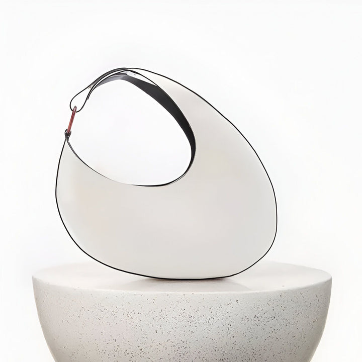 Sac blanc moderne avec anse noire posé sur un socle gris texturé., 46194017698016,46194017730784,46194017763552