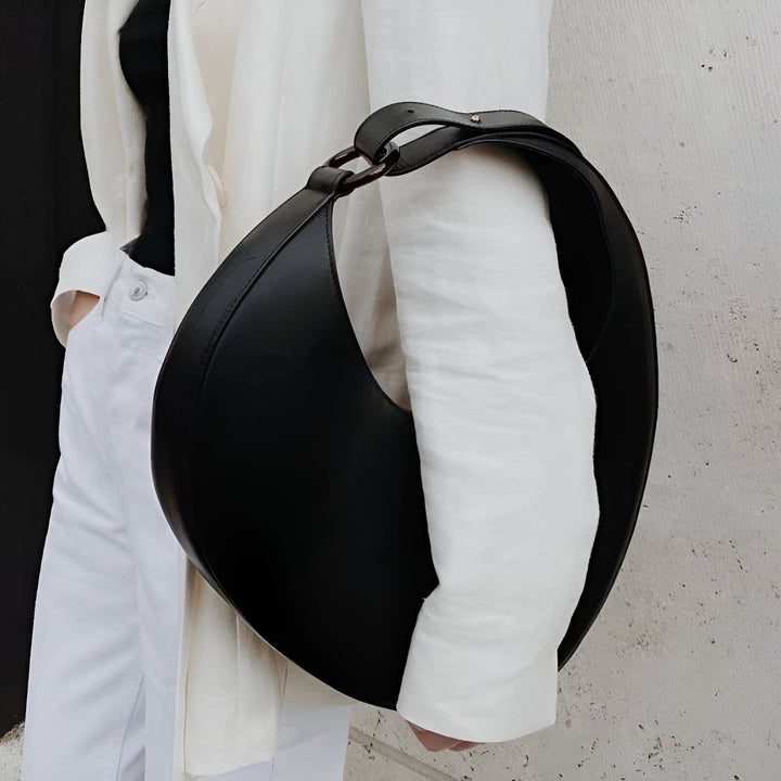 Personne avec sac à main noir en forme de lune et veste blanche., 46194017698016,46194017730784,46194017763552