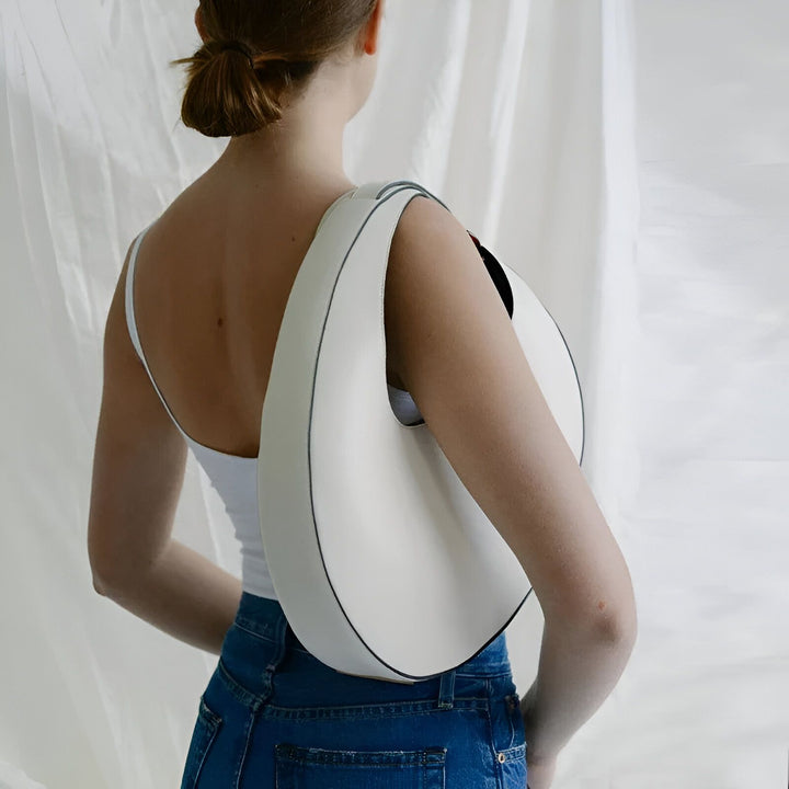 Sac blanc de forme courbée porté sur l'épaule d'une femme de dos., 46194017698016,46194017730784,46194017763552