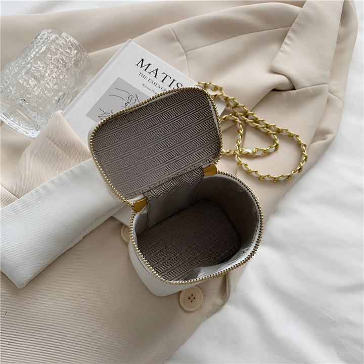 Mini sac blanc ouvert avec chaîne dorée et doublure à chevrons, posé sur un blazer avec livre., 46193974739168,46193974771936,46193974804704,46193974837472,46193974870240