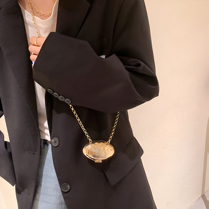 Collier chaîne dorée avec pendentif ovale porté sur un blazer noir., 46193973788896,46193973821664