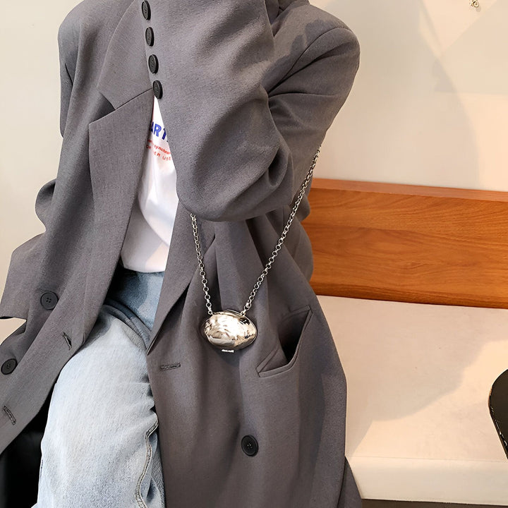 Détail d'une tenue : blazer gris, jean, sac argenté métallisé forme galet avec chaîne., 46193973788896,46193973821664