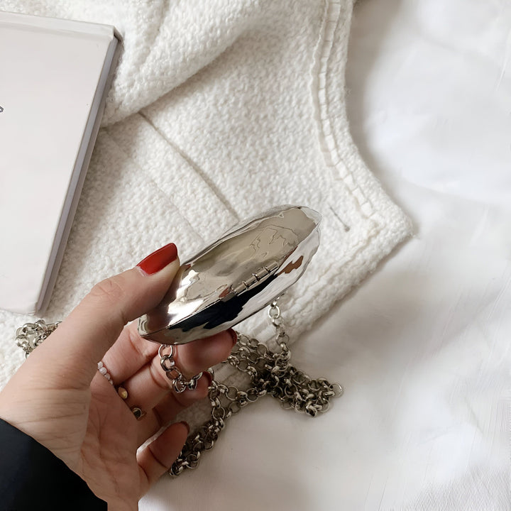 Pochette argentée brillante tenue par une main, avec chaîne épaisse., 46193973788896,46193973821664