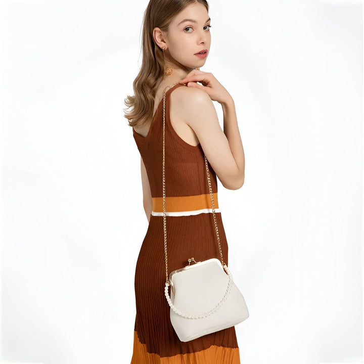 Femme en robe côtelée marron et orange tenant une pochette blanche avec chaîne., 46193949081824,46193949114592,46193949147360