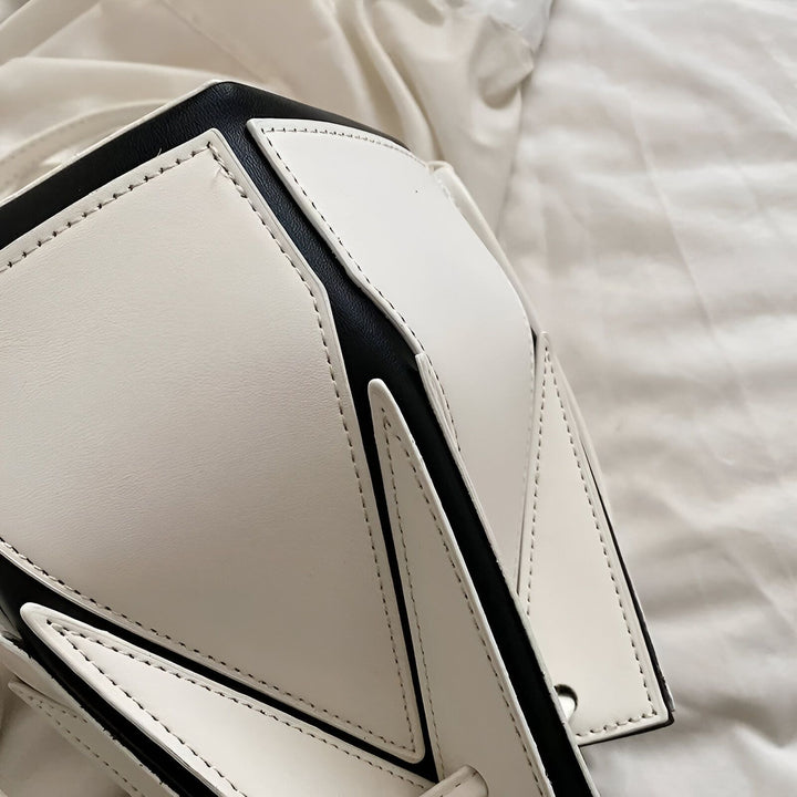 Gros plan sur un sac en cuir blanc et noir avec empiècements géométriques et surpiqûres., 46194005213408,46194005246176,46194005278944,46194005311712,46194005344480,46194005377248