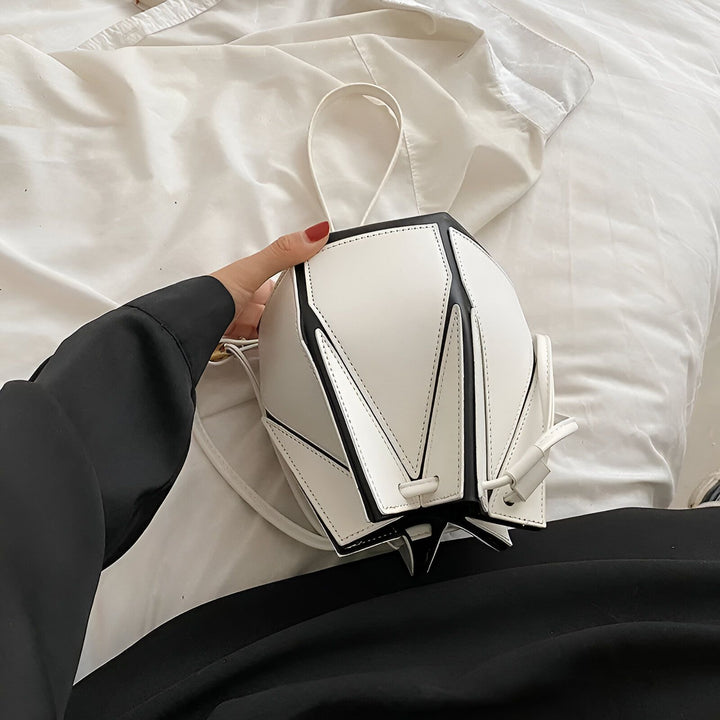 Sac à main blanc et noir forme géométrique tenu à la main., 46194005213408,46194005246176,46194005278944,46194005311712,46194005344480,46194005377248