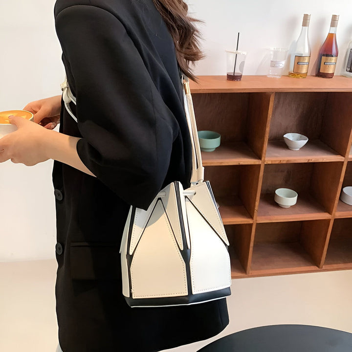 Sac seau bicolore blanc et noir porté par une personne tenant une tasse de café., 46194005213408,46194005246176,46194005278944,46194005311712,46194005344480,46194005377248