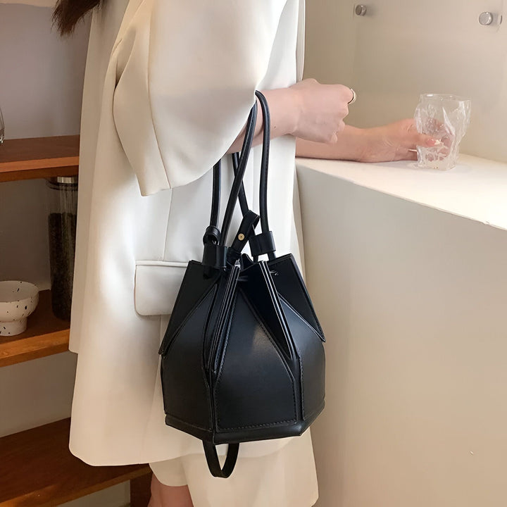 Femme tenant un sac à main noir structuré en cuir, portant un blazer blanc., 46194005213408,46194005246176,46194005278944,46194005311712,46194005344480,46194005377248