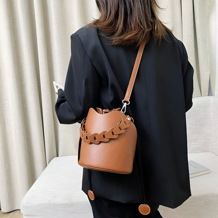 Sac seau marron avec anse chaîne porté par une femme en blazer noir, vue de dos., 46194008850656,46194008883424,46194008916192,46194008948960