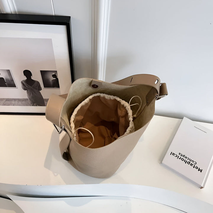 Sac seau en cuir beige ouvert avec doublure à cordon sur table., 46193881710816,46193881743584,46193881776352