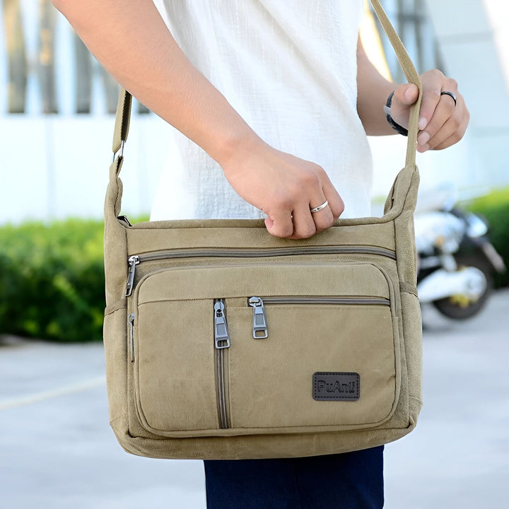 Sac bandoulière PuAnli beige en toile porté par un homme, avec multiples poches zippées., 46194061148384,46194061181152,46194061213920,46194061246688,46194061279456